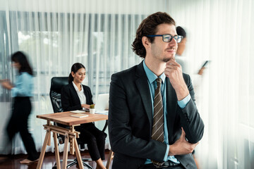 Portrait of happy businessman looking at camera with motion blur background of business people...