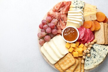Different types of cut cheese and other snacks on light textured table, top view. Space for text
