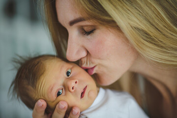 Young mother kissing cheek of her newborn son