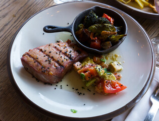Grilled tuna steak garnished with avocado and tomatoes