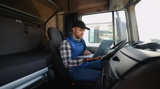 Truck driver reviewing trip documents on laptop before departure