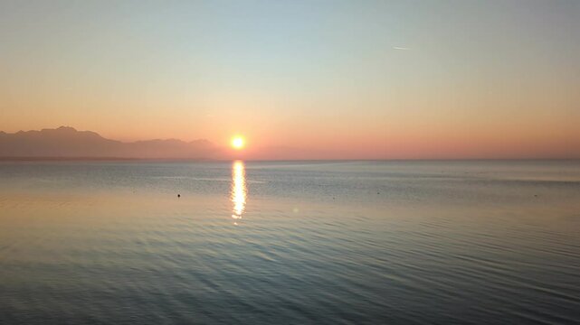 A breathtaking sunset over Lake Chiemsee, captured from Chieming, paints the sky in warm colors while the calm water reflects the glowing hues.