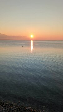 A breathtaking sunset over Lake Chiemsee, captured from Chieming, paints the sky in warm colors while the calm water reflects the glowing hues.