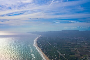 Coastal view of Barcelona showcasing the shoreline and lush landscape under a blue sky with wispy clouds