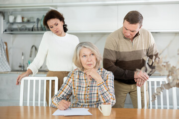 Old woman deciding and signing inheritance papers in family circle