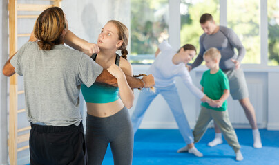 Adolescence girl in gym perform basic elements of krav maga self-defense system, sparring with male...