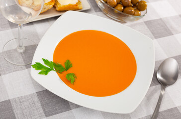 Traditional cold soup gazpacho in bowl served with vegetables and baked breads. Spanish cuisine