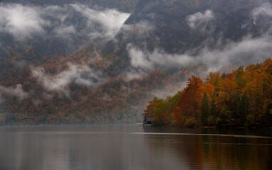 Fog rolling over mountain lake reflecting autumn forest