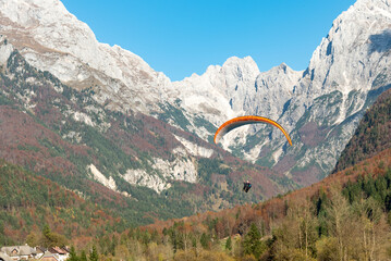 Paraglider flying over the julian alps in slovenia during autumn season