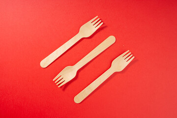 Three wooden eco-friendly forks diagonally on red background