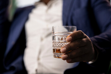 Two partners drinking glass of whiskey in the social club library, discuss career goals and perspectives to double fortune. Upper class elite gentlemen serving scotch and do business. Close up.