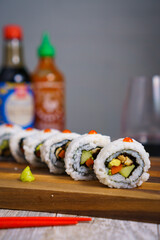 Delicious sushi platter with avocado rolls, California rolls and spicy sauce, ideal for restaurant menus, food blogs, and culinary magazines.