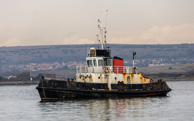Derelict harbour tug boat. Rusting at its mooring.