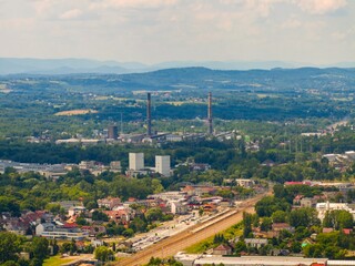 Industrial landscape of Krakow with factories and railways surrounded by green hills on a sunny day