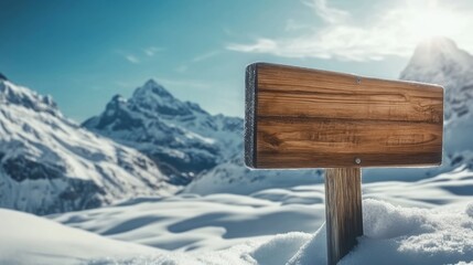 Naklejka premium Snow-covered landscape with a wooden sign in the foreground and majestic mountains in the background during bright daylight