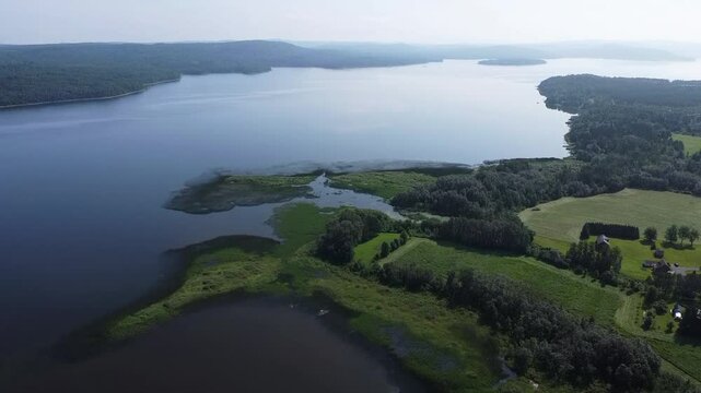 Aerial sweep over the expansive Lake Matapedia and its fog‑covered forested shores intersected by Route 132 in Quebec&rsquo;s Matapedia Valley