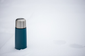 Blue hot thermos stands in snow background
