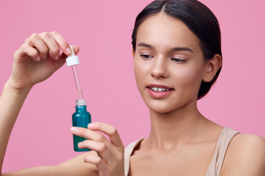 Young woman applying serum from a dropper bottle, promoting skincare and beauty with a fresh, vibrant mood