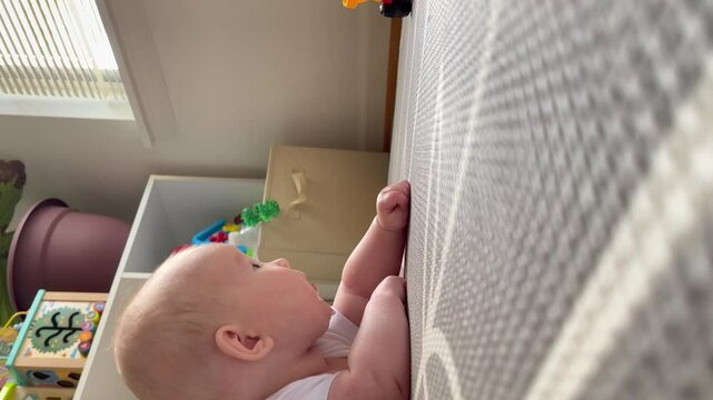 Cute Caucasian newborn baby girl during tummy time tracking the toy with her eyes. Healthy newborn baby development concept. Tummy time on a play mat. Baby playing with toy car