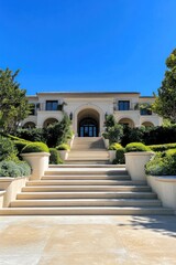 Fototapeta premium Majestic mansion showcasing elegant architecture and lush landscaping under a clear blue sky with vibrant greenery surrounding the grand staircase