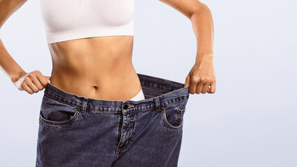 Successful Slimming. Closeup cropped view of fit young woman wearing too large jeans, demonstrating...