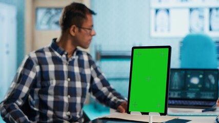 Indian woman medic consulting a patient next to isolated screen on tablet, ensuring easy recovery from disease. Physician at examination in medical office, review diagnostic reports. Camera A.