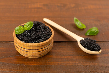 Bowl with black caviar on on wooden table