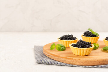 Tartlets with black caviar served on on wooden table © Liami
