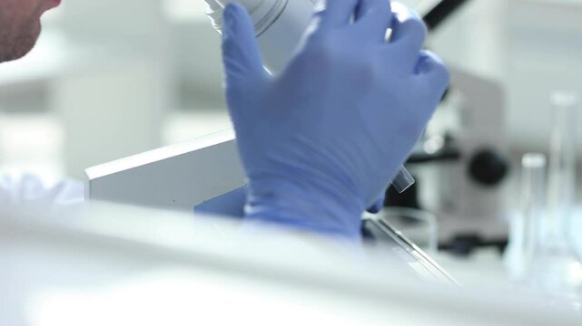 Assertive male scientist looking through a microscope