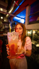 Mujer ofreciendo un cóctel en un bar moderno con iluminación de ambiente