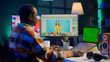 African american photo designer retouching images next to green screen on dual screens in tech driven environment, representing modern digital media. Graphic artist uses software tools. Camera A.
