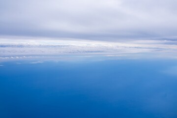 Obraz premium Sky and ocean blend seamlessly under a cloudy horizon captured from above the water