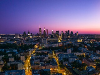 City skyline of Warsaw illuminated at dusk with a vibrant sky and busy streets below showcasing urban life