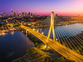 Obraz premium Beautiful sunset over Warsaw showcasing the illuminated bridge and city skyline