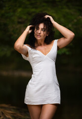 A serene portrait of a woman in a white dress, enjoying her holiday in the lush Daintree rainforest. Natural light highlights her curly hair & confident pose, celebrating grace & harmony with nature