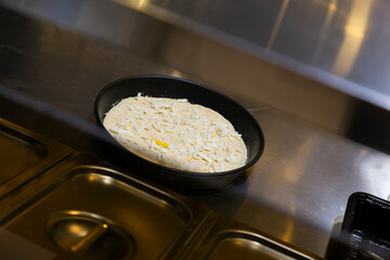 A pizza being prepared in a fast food restaurant kitchen. 