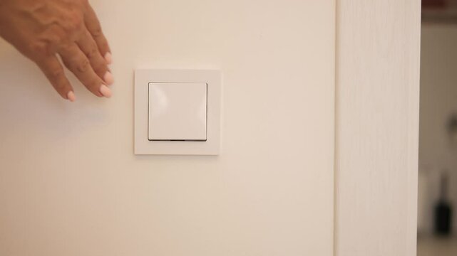 Woman turns room lighting on and off using wall switch Simple action highlights energy control and modern lighting Scene emphasizes practicality and aesthetics of home lighting solutions indoors