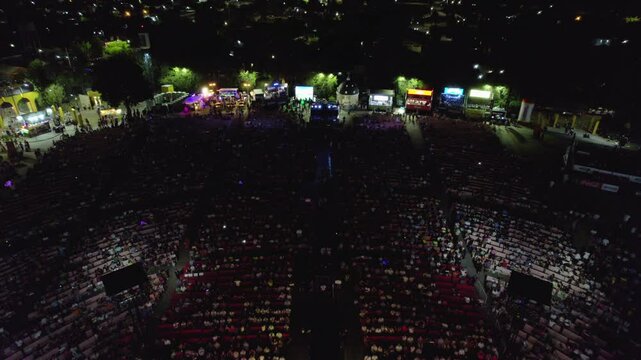 Dynamic Aerial View of a Live Concert with Crowded Stands and Cityscape Background