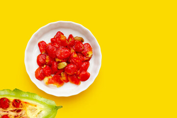 Bitter melon seeds in white plate on yellow background.