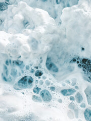 Naklejka premium A close-up view of what appears to be frothy water or foam. The foam is predominantly white with varying shades of blue, suggesting the presence of minerals or other elements in the water