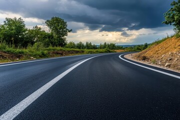 Fototapeta premium A long straight road through beautiful fields with trees along the road and wide open horizons.