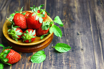 Fresh strawberry fruits and mint leaves on wooden  rustic background.