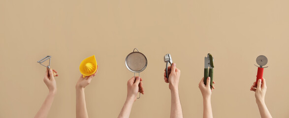 Female and male hands holding different kitchen utensils on brown background