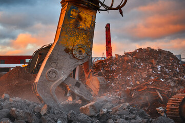 Powerful crusher destroys armored cement leftovers at sunset