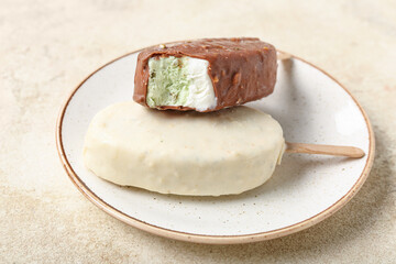 Plate with tasty chocolate covered ice cream on light background, closeup