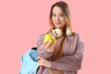 Female student with apple on pink background