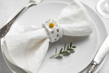 Plates with folded napkin, silver cutlery and glass on grunge white background
