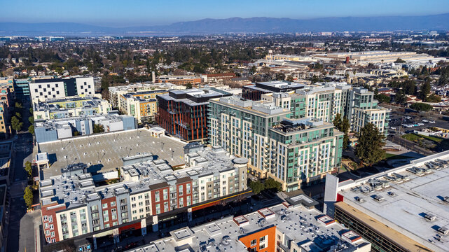 Aerial view of modern mixed-use development in downtown Sunnyvale, California. Residential and commercial buildings against mountain backdrop