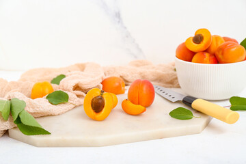 Board and bowl with fresh apricots on white background