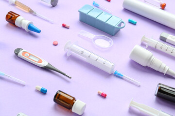 Composition with pills, thermometers and syringes on lilac background